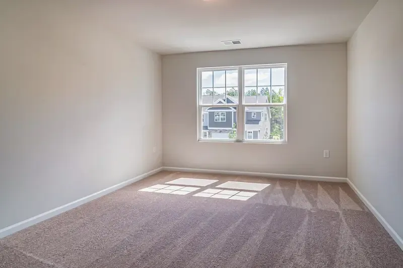 Bright, empty room with carpeted floor and large window.